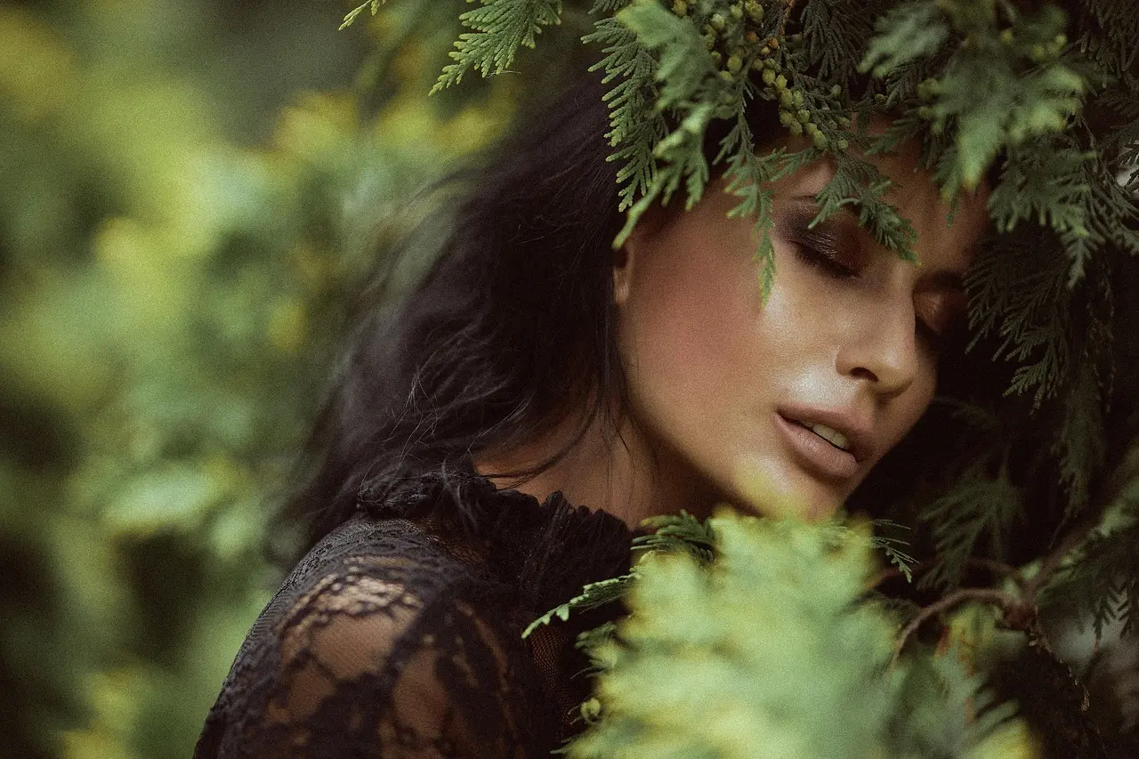 Kvinde med makeup omgivet af grønne grene