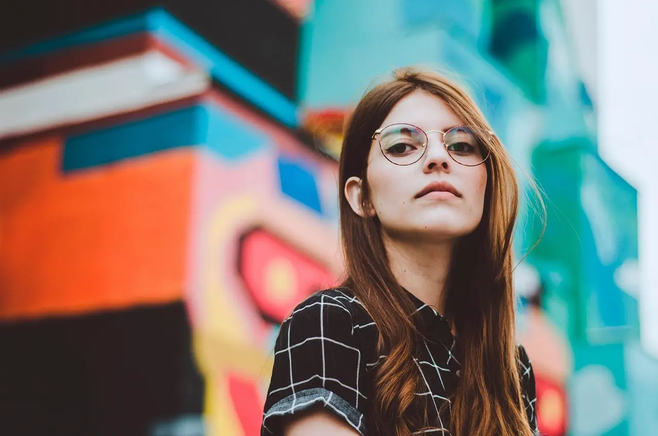 Ung kvinde med briller foran farverig væg